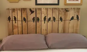 Testiera letto fai da te in legno di pallet con sagome di uccelli su un filo. Un progetto creativo per la tua camera da letto.