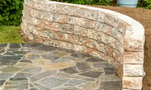 Muretti giardino fai da te in pietra naturale creano un percorso curvo e un'area rialzata.