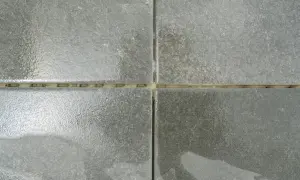 Dettaglio di piastrelle grigie con fughe giallastre. Una guida visiva su come stuccare le piastrelle per un risultato perfetto.