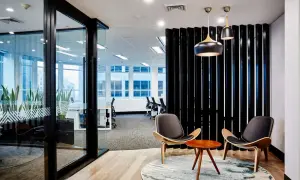 Un ufficio moderno con una parete divisoria in listelli neri, ideale per chi cerca come realizzare una parete divisoria economica. Due sedie di design e un tavolino completano l'area.
