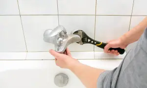 Mano con chiave inglese ripara un rubinetto cucina perde.