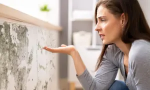 Donna preoccupata osserva muffa su muro. Scopri come togliere umidità in casa per un ambiente più sano.