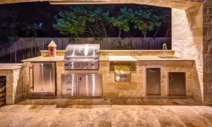 Cucina esterna in muratura fai da te con barbecue, frigo, lavello e piano di lavoro in granito.