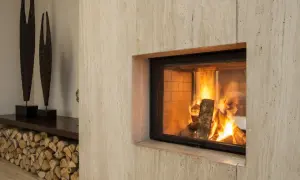 Un camino moderno con fiamme vive, pronto per lo spazzacamino. Legna accatastata e sculture decorative completano l'arredo.