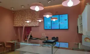 Lampadari rosa a forma di fungo illuminano un locale con pareti rosa e una parete fiorita. Un esempio di come abbinare due lampadari nella stessa stanza, creando un'atmosfera dolce.