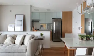 Un divano accogliente e quadri moderni separano visivamente la zona giorno dalla cucina e sala da pranzo, creando un ambiente armonioso.