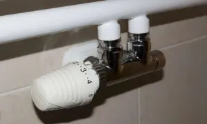 Valvole termostatiche cromate su vecchi termosifoni bianchi, con numeri per regolare la temperatura.