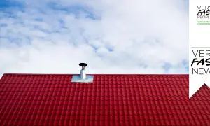 Tegole rosse e canna fumaria su tetto, per la manutenzione canna fumaria privata in condominio. Cielo azzurro con nuvole bianche.