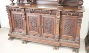 Mobile intagliato in legno scuro, con ante decorate e piedini a zampa di leone, tipico dell'epoca.