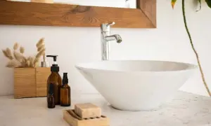 Un lavandino che perde, con flaconi ambrati e sapone in un portasapone di legno.