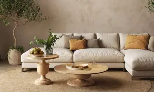 Un divano componibile beige, tavolini in legno, piante e cuscini color ocra creano salotti caldi e accoglienti, perfetti per rilassarsi.