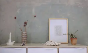 Parete con effetto materico, ideale per chi vuole imparare come pitturare una parete con stile. Arredamento minimalista con vasi, candela e quadro.