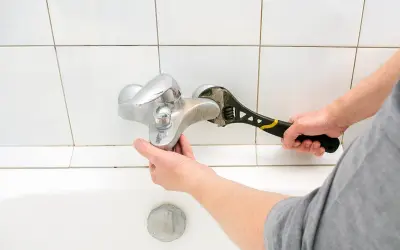 Mano con chiave inglese ripara un rubinetto cucina perde.