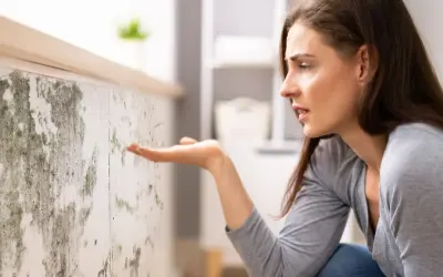 Donna preoccupata osserva muffa su muro. Scopri come togliere umidità in casa per un ambiente più sano.