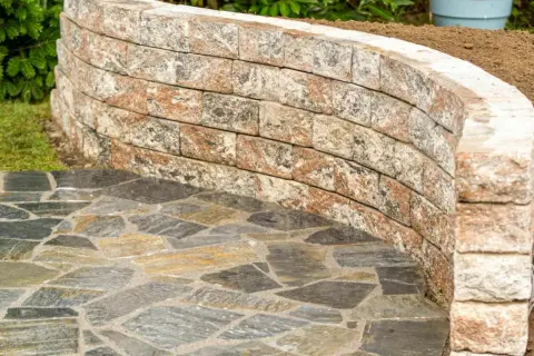 Muretti giardino fai da te in pietra naturale creano un percorso curvo e un'area rialzata.