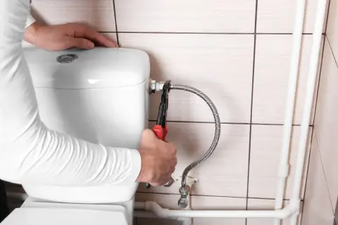 Mani con pinza che lavorano sul tubo flessibile per chiudere acqua cassetta wc.