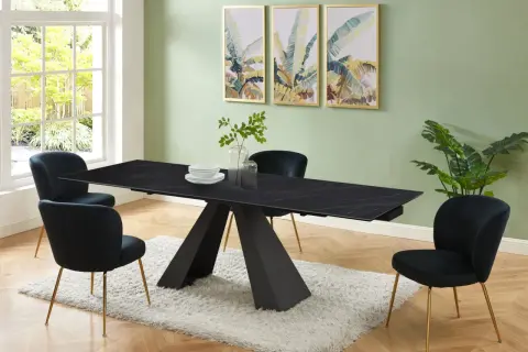 Elegante sala da pranzo con tavolo nero e sedie in velluto blu. Il colore pareti sala da pranzo è un verde tenue, che contrasta con le stampe tropicali.