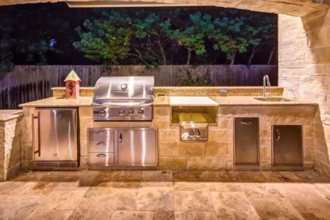Cucina esterna in muratura fai da te con barbecue, frigo, lavello e piano di lavoro in granito.