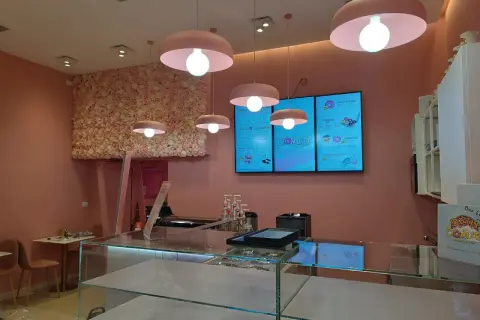Lampadari rosa a forma di fungo illuminano un locale con pareti rosa e una parete fiorita. Un esempio di come abbinare due lampadari nella stessa stanza, creando un'atmosfera dolce.