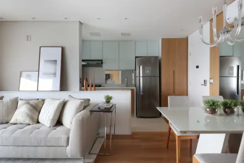Un divano accogliente e quadri moderni separano visivamente la zona giorno dalla cucina e sala da pranzo, creando un ambiente armonioso.