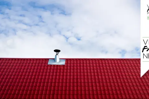 Tegole rosse e canna fumaria su tetto, per la manutenzione canna fumaria privata in condominio. Cielo azzurro con nuvole bianche.