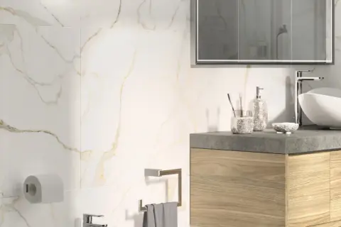 Bagno moderno con piastrelle effetto marmo e oro. Lavabo bianco, mobile in legno, specchio e accessori. Guida su come posare le piastrelle del bagno.