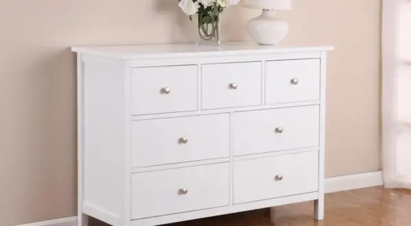 Cassettiera bianca a sette cassetti, ideale per rinnovare la camera da letto. Sopra, fiori e lampada.