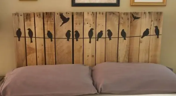 Testiera letto fai da te in legno di pallet con sagome di uccelli su un filo. Un progetto creativo per la tua camera da letto.