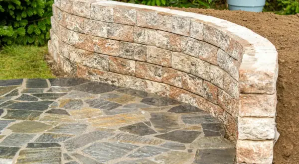 Muretti giardino fai da te in pietra naturale creano un percorso curvo e un'area rialzata.