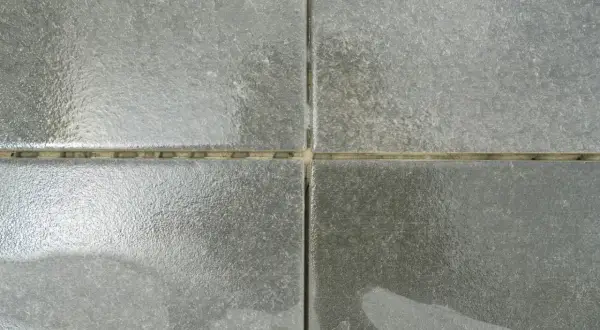 Dettaglio di piastrelle grigie con fughe giallastre. Una guida visiva su come stuccare le piastrelle per un risultato perfetto.
