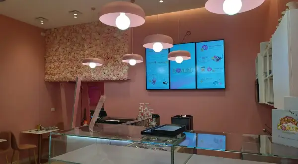 Lampadari rosa a forma di fungo illuminano un locale con pareti rosa e una parete fiorita. Un esempio di come abbinare due lampadari nella stessa stanza, creando un'atmosfera dolce.