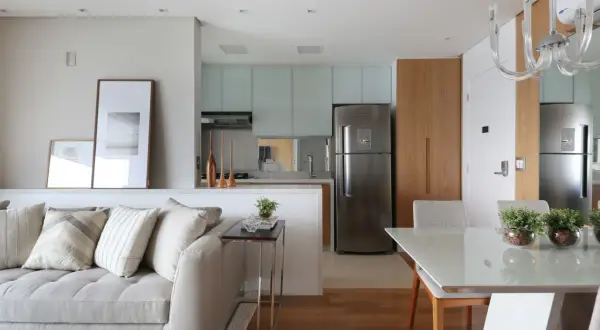 Un divano accogliente e quadri moderni separano visivamente la zona giorno dalla cucina e sala da pranzo, creando un ambiente armonioso.