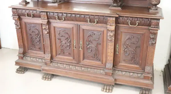 Mobile intagliato in legno scuro, con ante decorate e piedini a zampa di leone, tipico dell'epoca.