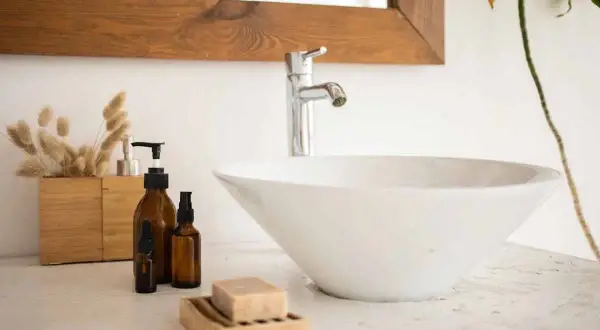 Un lavandino che perde, con flaconi ambrati e sapone in un portasapone di legno.