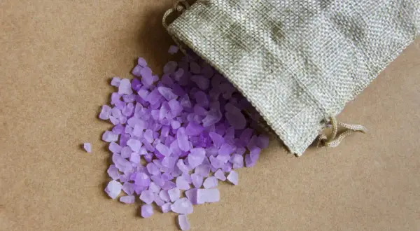 Sacchetti anti umidità fai da te con cristalli viola che fuoriescono da un sacchetto di juta.