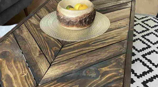 Tavolino con pallet fai da te, con ciotola di frutta e tappeto geometrico.
