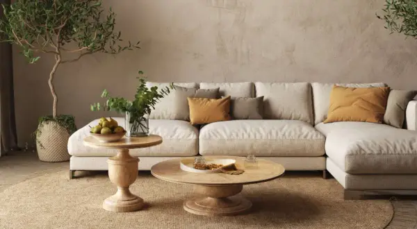 Un divano componibile beige, tavolini in legno, piante e cuscini color ocra creano salotti caldi e accoglienti, perfetti per rilassarsi.