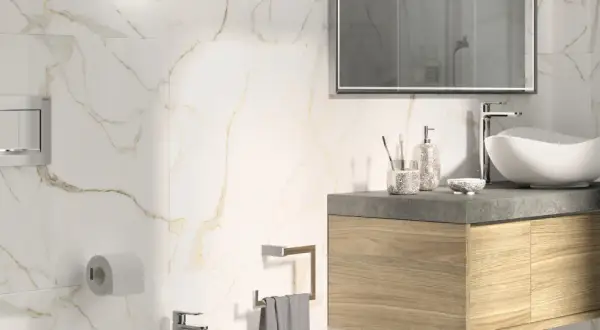 Bagno moderno con piastrelle effetto marmo e oro. Lavabo bianco, mobile in legno, specchio e accessori. Guida su come posare le piastrelle del bagno.