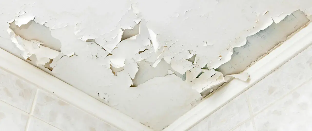 Soffitto scrostato e macchiato, segnale evidente di come riconoscere le infiltrazioni d'acqua. La pittura si stacca a chiazze, rivelando l'umidità sottostante.