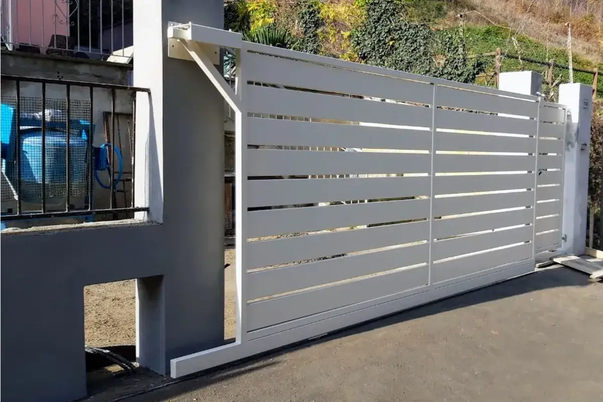 Nuovo cancello scorrevole bianco installato su solide fondamenta per un accesso sicuro e moderno.