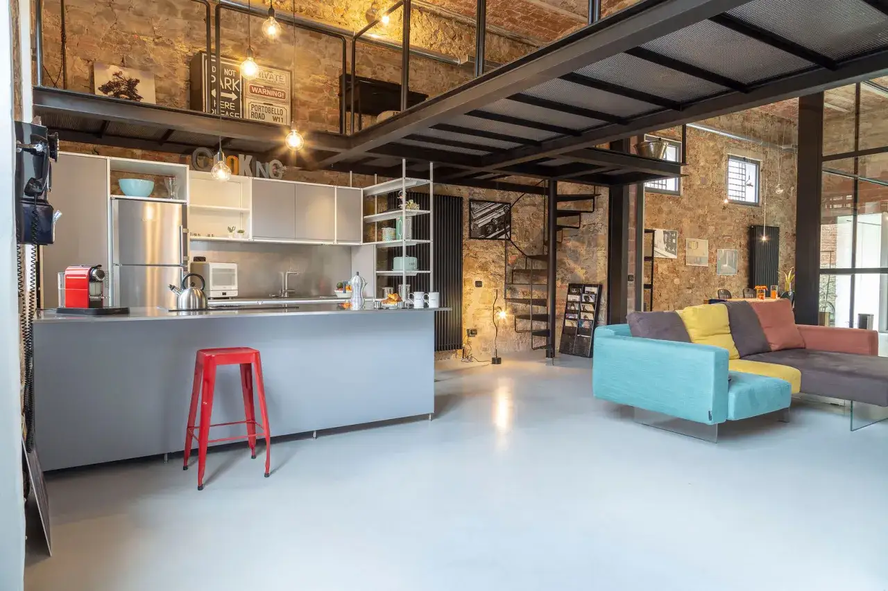 Interni con cucina moderna, divano colorato e soppalco in metallo, in perfetto stile industriale.