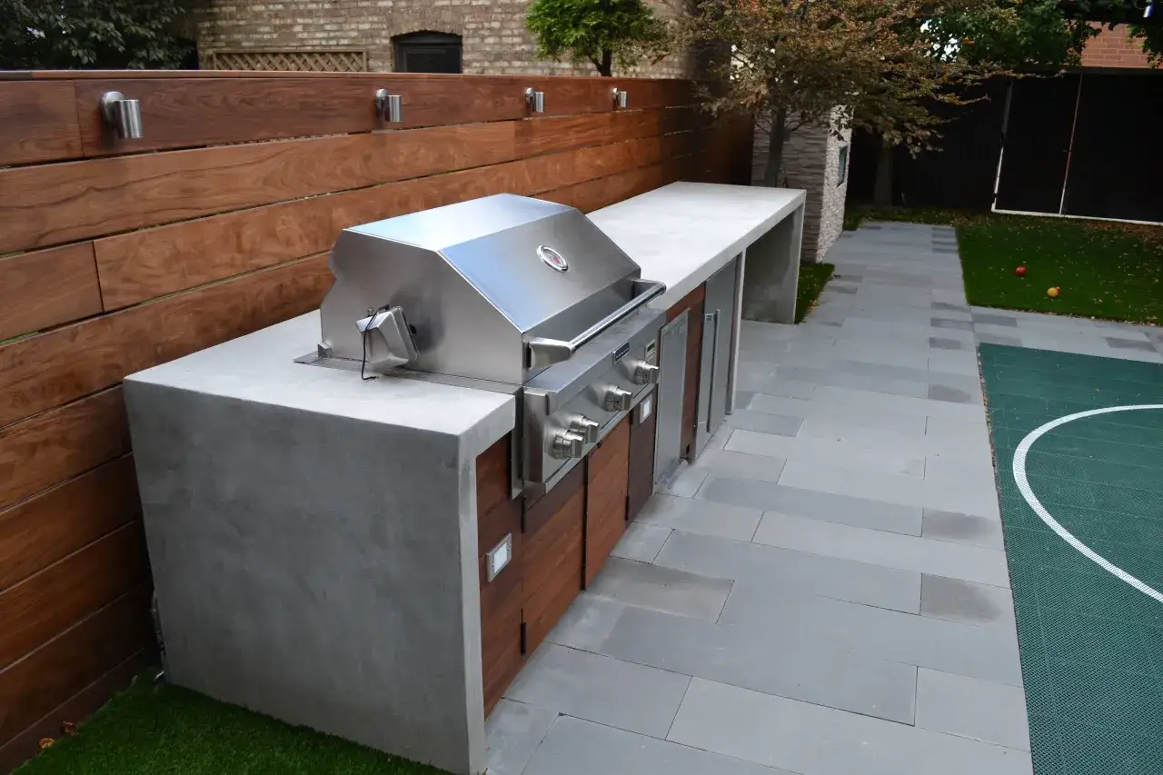 Cucina esterna in muratura fai da te con barbecue in acciaio inox, piano in cemento e finiture in legno. Perfetta per grigliate estive.