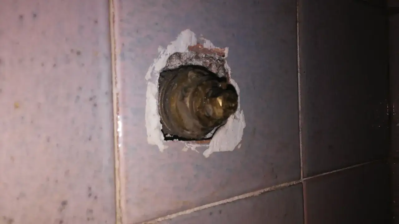 Valvola ottone incassata nel muro, parte di un impianto idraulico. La chiusura acqua è visibile, con residui di stucco attorno.