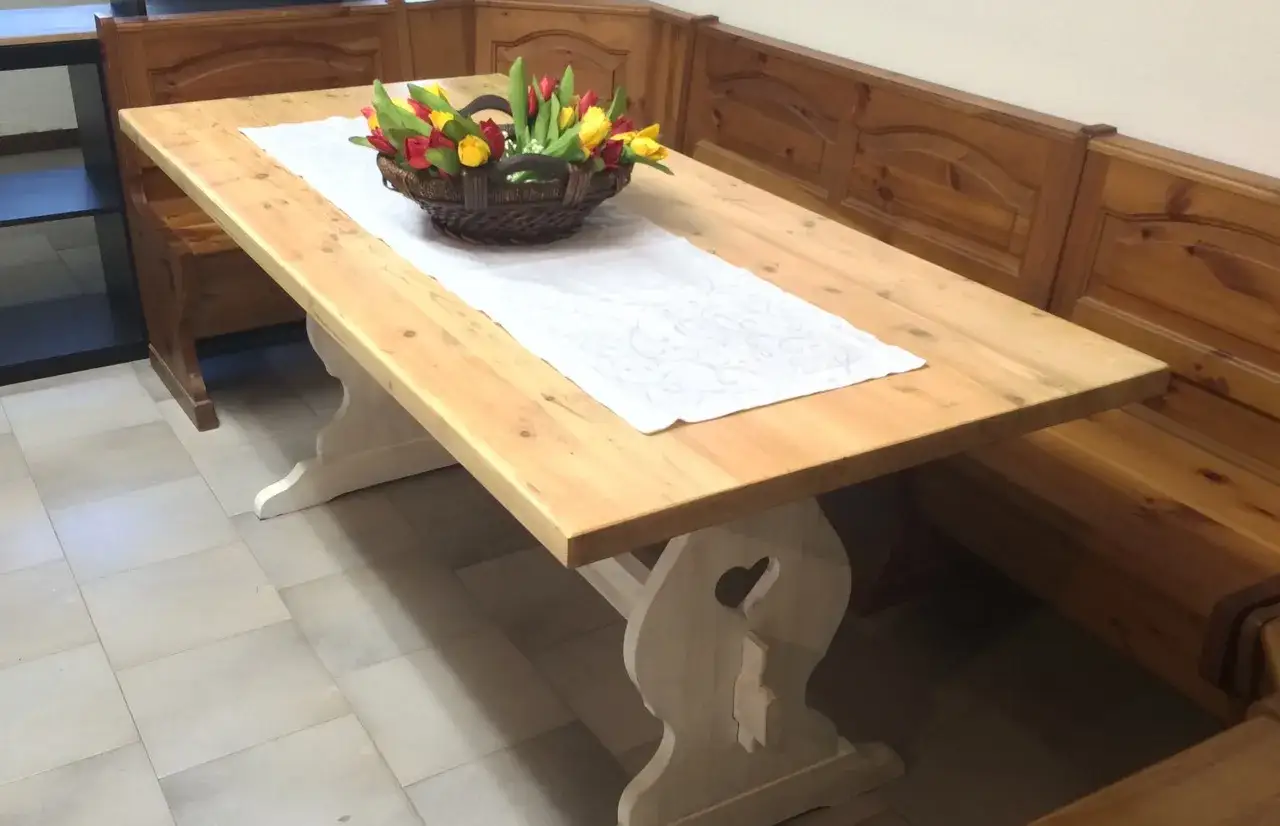 Tavolo in legno chiaro, pronto per restaurare un tavolo in stile shabby. Un cesto di tulipani decora la tovaglia bianca.