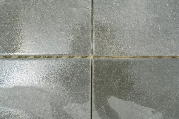 Dettaglio di piastrelle grigie con fughe giallastre. Una guida visiva su come stuccare le piastrelle per un risultato perfetto.