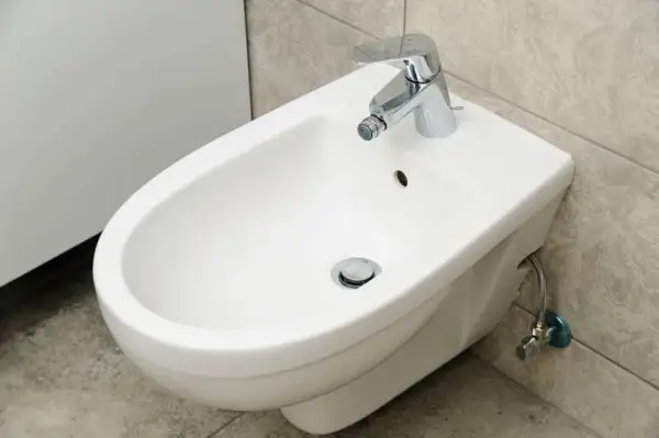 Bidet bianco con rubinetto cromato. Se hai problemi a sturare il bidet, questo è il primo passo per risolvere.