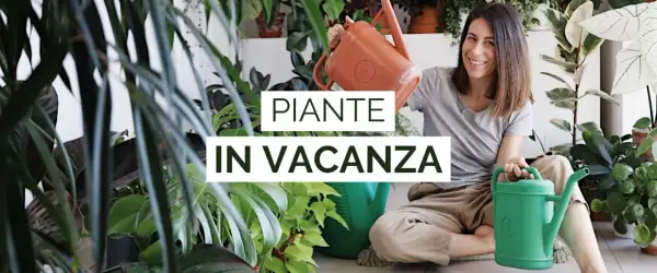 Donna sorridente con annaffiatoi, circondata da piante rigogliose. Impara come innaffiare le piante quando si va in vacanza per mantenerle sane.