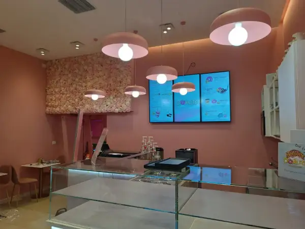 Lampadari rosa a forma di fungo illuminano un locale con pareti rosa e una parete fiorita. Un esempio di come abbinare due lampadari nella stessa stanza, creando un'atmosfera dolce.