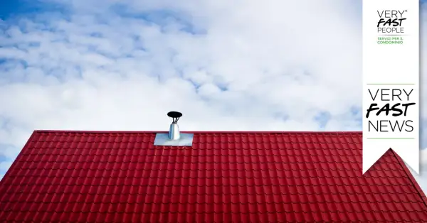 Tegole rosse e canna fumaria su tetto, per la manutenzione canna fumaria privata in condominio. Cielo azzurro con nuvole bianche.