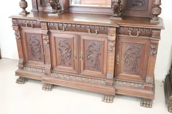 Mobile intagliato in legno scuro, con ante decorate e piedini a zampa di leone, tipico dell'epoca.